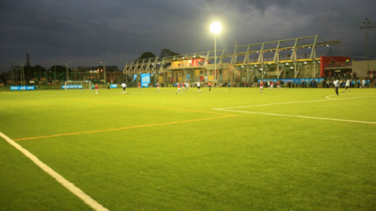 La cancha esta iluminada y tiene grama sintética|||