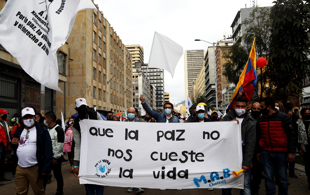 Marcha de las FARC encabezadas por Pastor Alape y por Carlos Lozada|Marcha de las FARC por la Séptima de Bogotá|Fin de la Marchas en la Plaza Simón Bolívar|Imagen de un ex combatiente asesinado en una pancarta de las FARC|Pancarta con la palabra Paz de las FARC|Pancarta &#039;Somos el grito de los que ya no están&#039;|Performance de un actor y activista en las marchas de las FARC|Retrato en las marchas de las FARC|||