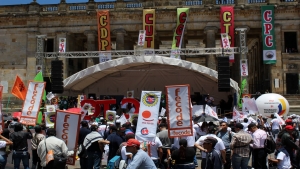 La tarima de los líderes sindicales ubicada delante del Congreso de la República.|Miembros de la Confederación de Trabajadores de Colombia marchan|Directores de varios sindicatos y organizaciones laborales en el acto central en la Plaza de Bolívar|Campaña &quot;Nico vive&quot;|Miembros de la Confederación General del Trabajo durante la marcha del 1 de Mayo|Miembro de Partido Comunista marcha en frente de efectivos de la Policía|Los manifestantes recorriendo la carrera Séptima para llegar a la Plaza de Bolívar.|Estudiantes de la Universidad Cooperativa de Colombia marchan|Algunos manifestantes también se pronunciaban sobre el asesinato de líderes sociales en el país|Miembros del sindicato Memoria Viva en su entrada a la plaza para la reunión de todos los manifestantes|Una de las representaciones simbólicas de la paz en la carrera Séptima y debajo la bandera de la Unión Patriótica.|Manifestantes frente a la Catedral Primada con una bandera de la causa comunista|Los bailes típicos y la música robaron la atención del público dentro de la marcha|El Presidente de la asociación de las familias de las víctimas de la sociedad civil de soldados, policías y guardias de Colombia atiende la protesta|Los tambores se sumaron a las voces de denuncia dentro de la Plaza de Bolívar|||
