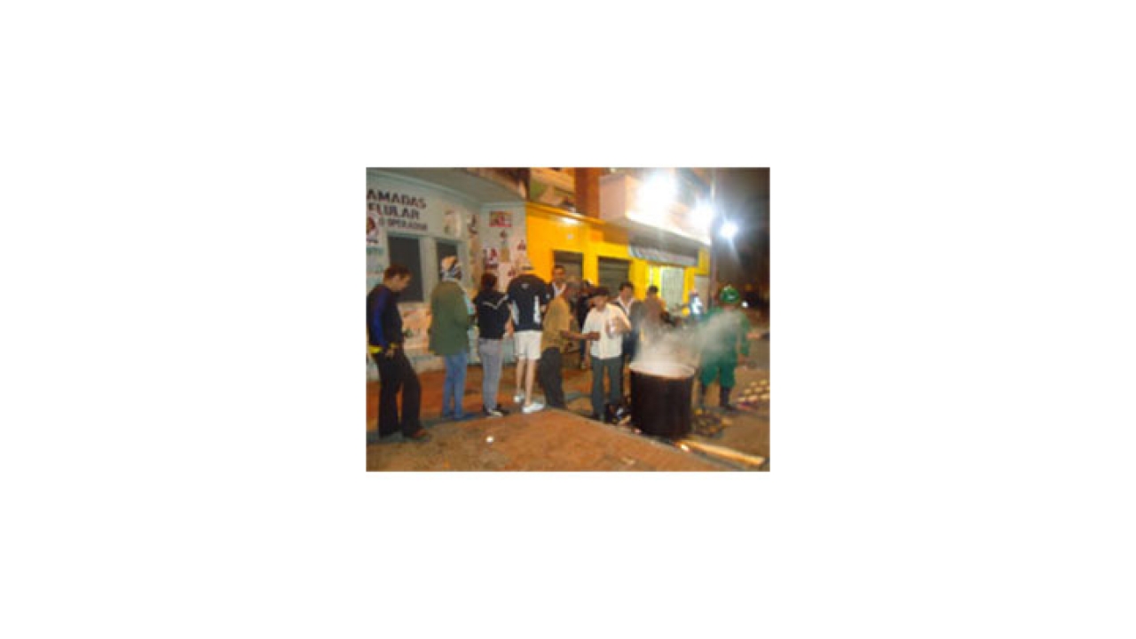 A pesar de la lluvia, las personas se mantienen en la fila para recibir agua de panela.|||