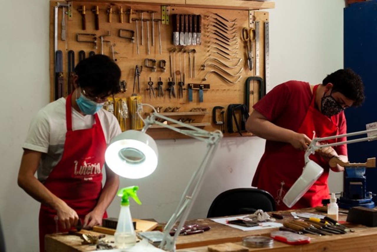 Luis Felipe y su compañero en el proceso de creación de violín.|Luis Felipe y su maestro en el proceso de creación de violín.|Luis Felipe en el proceso de creación de violín.|Violín participante de concurso de la Fundación Salvi.|Luis Felipe en el medio con su maestro y compañeros en el taller.|El precio de los instrumentos hechos por lutieres  oscilan entre los 3 y 10 millones de pesos colombianos.|Trabajo en el taller.|||