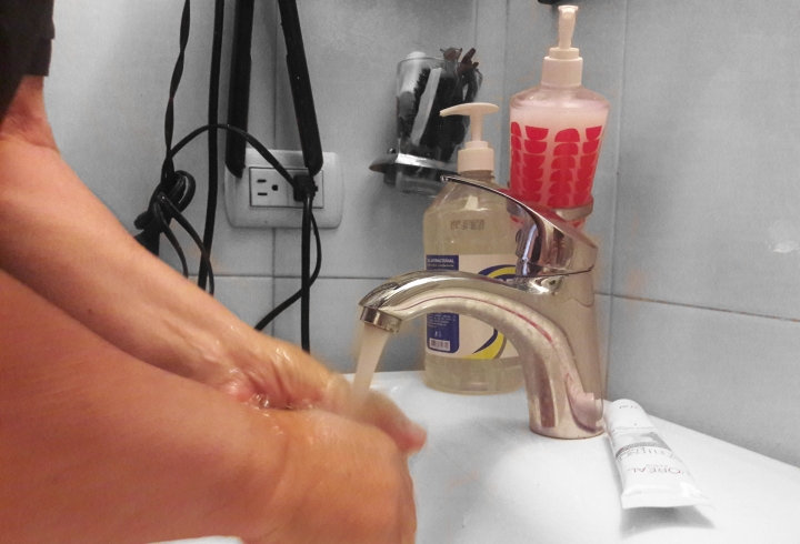 Padre de familia lav&aacute;ndose las manos en el ba&ntilde;o de su hogar