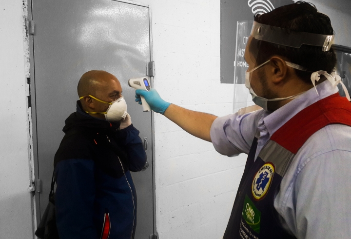 Empleado de Homecenter tomando la temperatura mediante un term&oacute;metro electr&oacute;nico a un cliente para verificar su estado de salud y permitirle ingresar