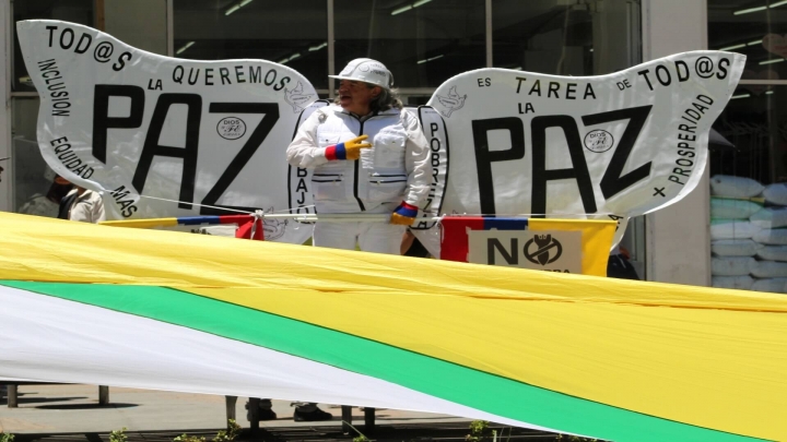 Una de las representaciones simb&oacute;licas de la paz en la carrera S&eacute;ptima y debajo la bandera de la Uni&oacute;n Patri&oacute;tica.