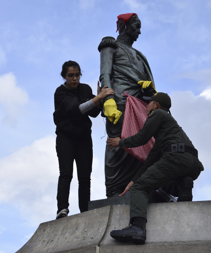 Una joven se mont&oacute; en la estatua de Sim&oacute;n Bol&iacute;var en la Plaza de Bol&iacute;var y, bajo la consigna de que los hombres tambi&eacute;n entran a la cocina, lo vistieron con delantal y guantes para lavar la loza. A penas se dio cuenta la Polic&iacute;a, subieron un bachiller para que la bajara y le quitara los atuendos a la estatua. Foto: Santiago Luque